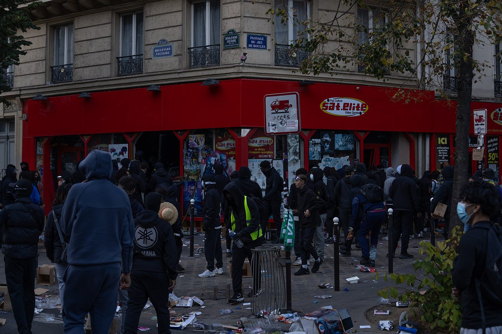 Foule de jeunes en capuche devant un magasin d'électronique pillé à l'angle du boulevard Voltaire, à Paris