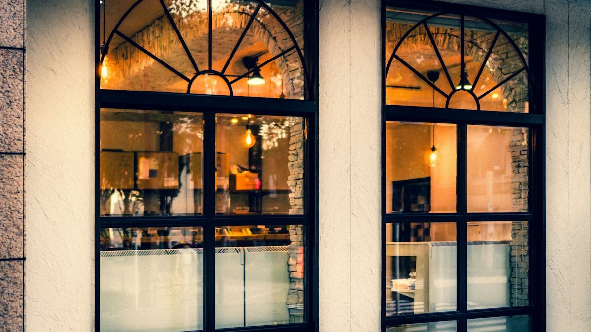 Vitrines d'une boutique éclairée, menuiseries noires et grandes surfaces vitrées en façade